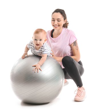 Genç sportif anne ve bebeği beyaz arka planda fitball ile egzersiz yapıyorlar.