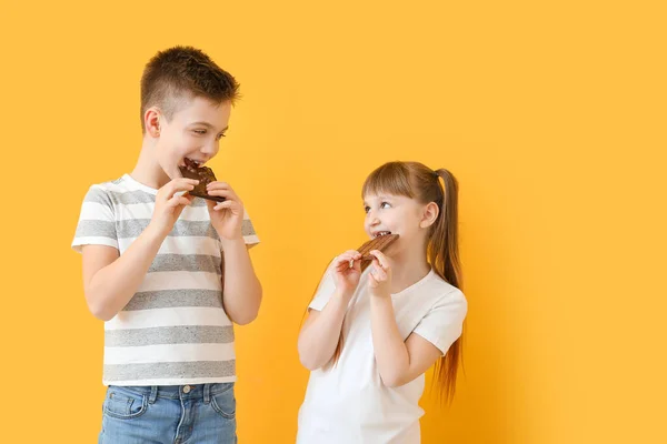 Lindos Niños Pequeños Comiendo Chocolate Sobre Fondo Color — Foto de Stock