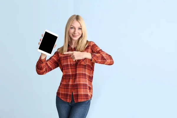 Beautiful young woman with tablet computer on color background