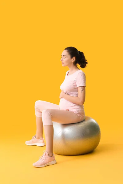 年轻的怀孕妇女带着彩色背景的皮球做运动 — 图库照片