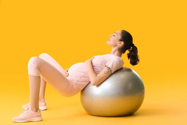 年轻的怀孕妇女带着彩色背景的皮球做运动 — 图库照片
