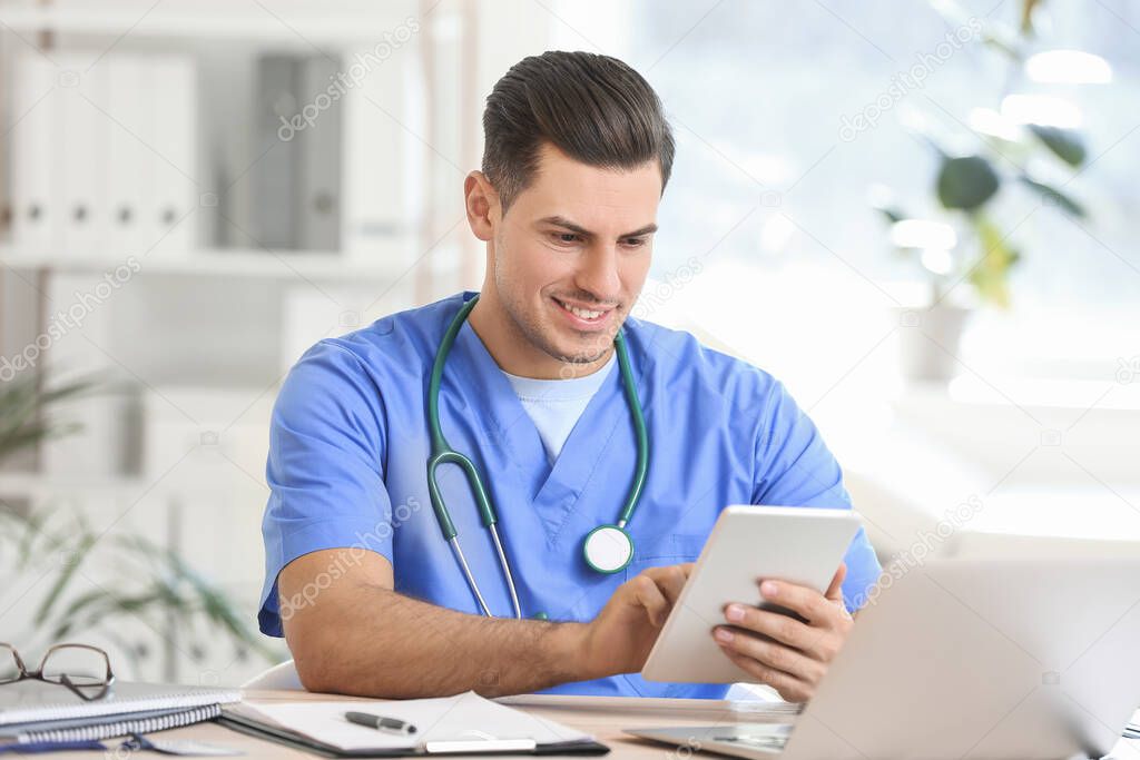 Young male doctor with tablet computer working in clinic