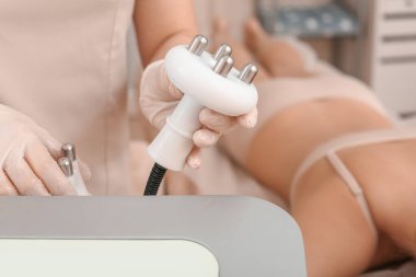 Klinikte anti-selülit masajı için modern ekipmanlara sahip kozmetolog, yakın plan.