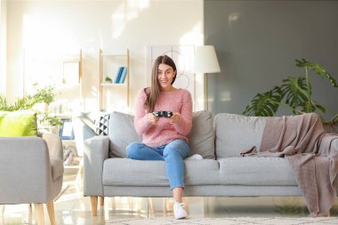 Evde video oyunu oynayan güzel genç bir kadın.