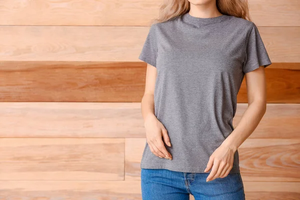 木製の背景にスタイリッシュなTシャツの女性 — ストック写真