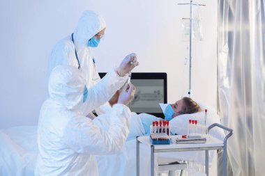 Biyolojik tehlike giysileri içindeki doktorlar bulaşıcı izolasyon koğuşundaki hastalarla çalışıyorlar. Coronavirüs salgını kavramı