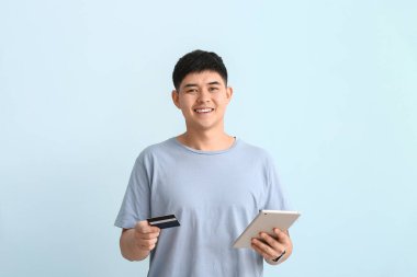 Kredi kartı ve tablet bilgisayarı olan Asyalı bir adam.