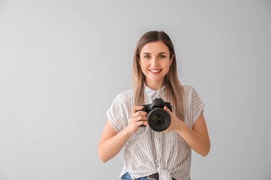 Gri arka planda modern kameralı kadın fotoğrafçı.