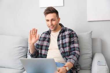 Genç adam evde video sohbeti yapıyor.