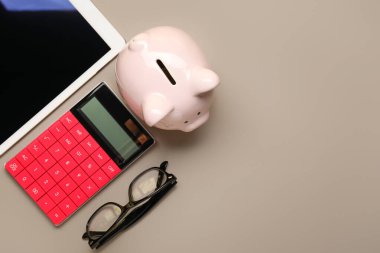Kumbaralı hesap makinesi, gri arka planda tablet bilgisayar ve gözlük.