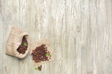 Ahşap arka planda kahve çekirdekleri olan çanta.