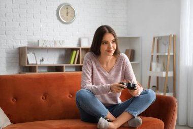 Evde video oyunu oynayan güzel genç bir kadın.