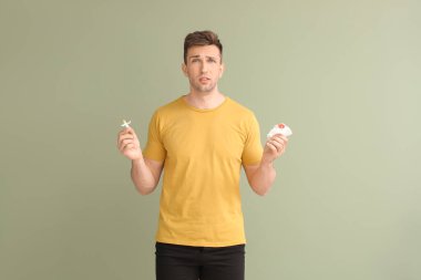 Hemoroidal fitil ve arka planda kan içinde tuvalet kağıdı olan genç bir adam.