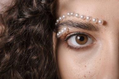 Güzel kıvırcık saçlı ve yaratıcı makyajlı genç kadın, yakın plan.