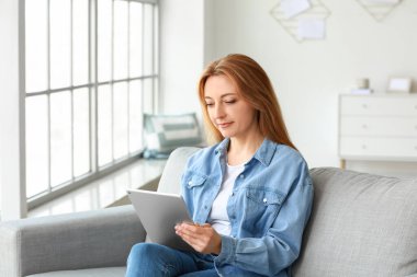 Evde online öğrenim için tablet bilgisayar kullanan olgun bir kadın