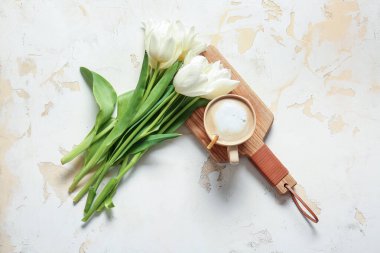 Hafif arka planda bir fincan kahve ve bir buket çiçek