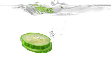 Taze salatalık dilimleri beyaz arka planda suya düşer.