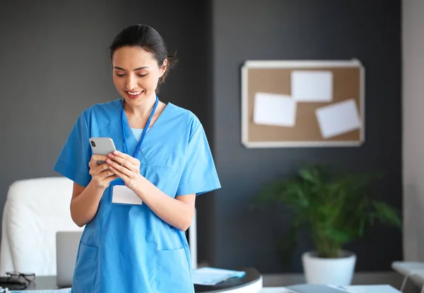 Portrait of young female doctor with mobile phone in clinic