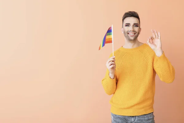 Lgbtの旗を持つ若いトランスジェンダーの女性の肖像色の背景にOkジェスチャーを示しています — ストック写真
