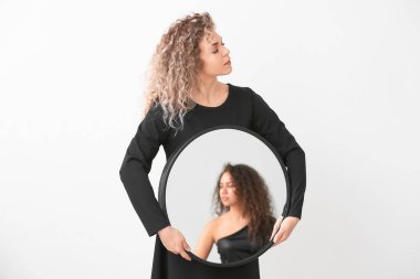 Beautiful model holding mirror with reflection of young woman on white background