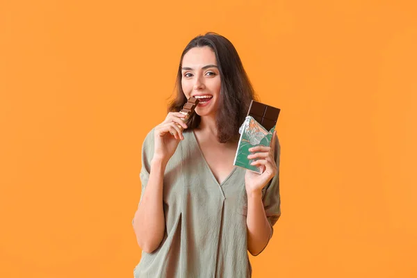 Hermosa Mujer Joven Comiendo Sabroso Chocolate Fondo Color —  Fotos de Stock