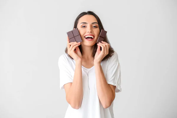 美しい若い女性が白い背景においしいチョコレートを食べる — ストック写真