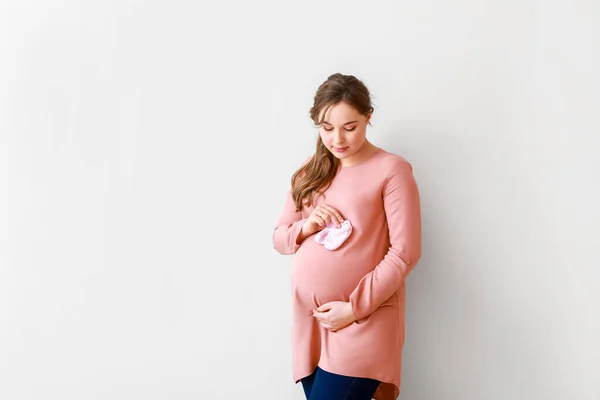 Schöne Schwangere Frau Mit Babyschuhen Auf Hellem Hintergrund — Stockfoto