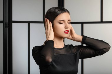 Gri arka planda güzel makyajlı genç bir kadın.