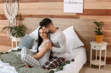 Mutlu genç çift evde yatakta oturuyor.