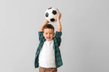 Gri arka planda futbol topu olan şirin bir çocuk.