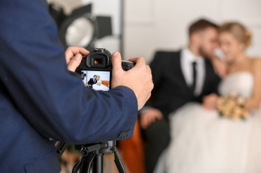 Stüdyoda genç bir çiftle çalışan fotoğrafçı, yakın plan.