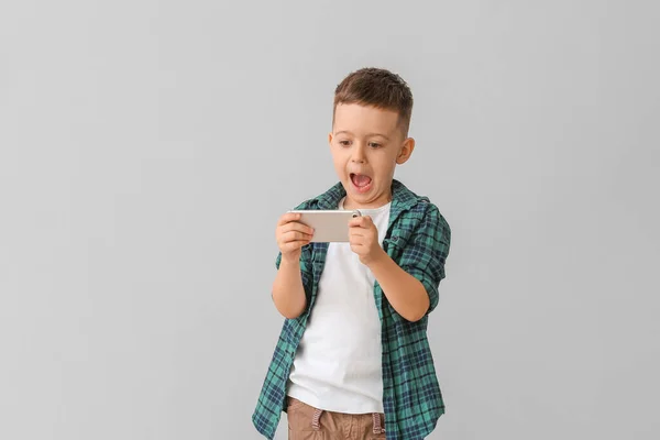 Niño Sorprendido Con Teléfono Móvil Sobre Fondo Gris — Foto de Stock