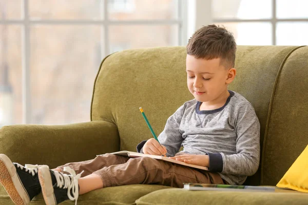 Niedlicher Kleiner Junge Mit Notizbuch Sitzt Auf Dem Sofa Hause — Stockfoto