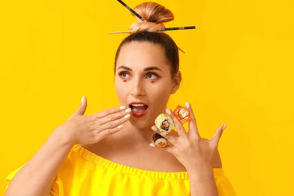 Beautiful woman with tasty sushi on color background