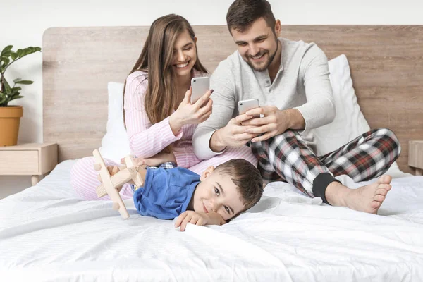 Little Boy His Parents Mobile Phones Bedroom — Stock Photo, Image