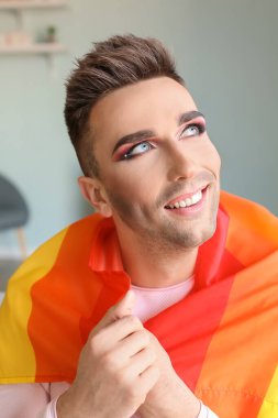Evde LGBT bayrağı taşıyan genç transseksüel kadın portresi