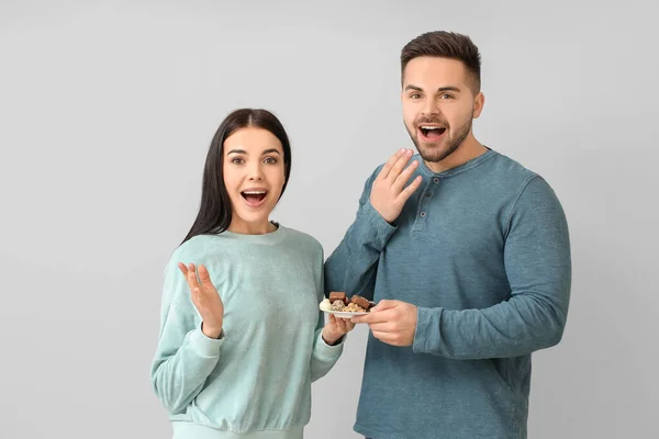 Surprised Young Couple Tasty Chocolate Light Background — Stock Photo, Image