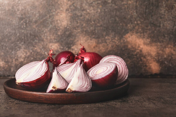 Plate with fresh raw onion on grey background