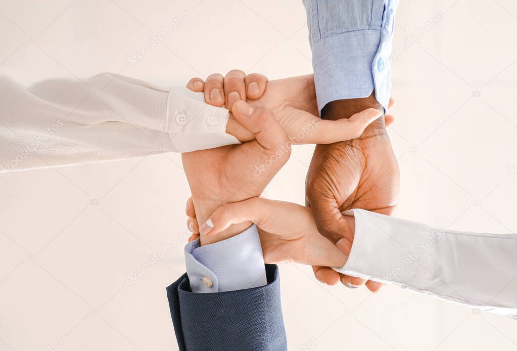 Group of business people holding hands together in office, bottom view. Unity concept
