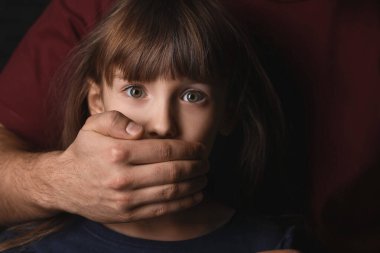 Baba korkmuş küçük kızının ağzını kapatıyor, yakın plan. Aile içi şiddet kavramı