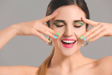 Gri arka planda güzel manikürlü genç bir kadın.