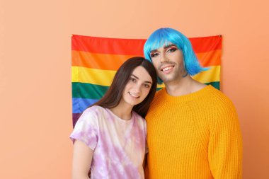 Renkli arka planda LGBT bayrağı taşıyan genç transseksüel çiftin portresi