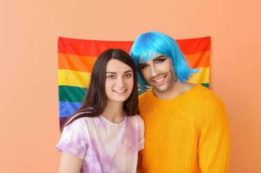 Renkli arka planda LGBT bayrağı taşıyan genç transseksüel çiftin portresi