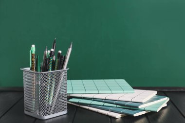 Tahtanın yanındaki masada kırtasiye malzemesi olan tutucu