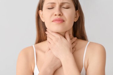 Young woman checking thyroid gland on grey background clipart