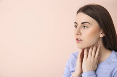 Genç bir kadın arka planda tiroit bezini kontrol ediyor.