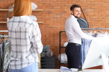 Müşteri modern kuru temizlemeciden kıyafet alıyor.