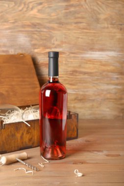 Ahşap zemin üzerinde şarap şişesi olan bir kutu.
