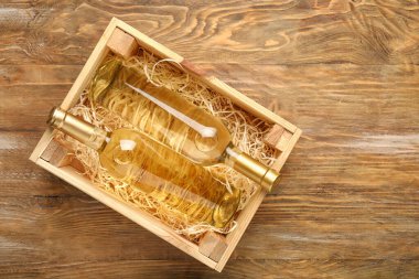 Ahşap arka planda şarap şişeleri olan bir kutu.