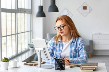 Evde online öğrenim için tablet bilgisayar kullanan olgun bir kadın